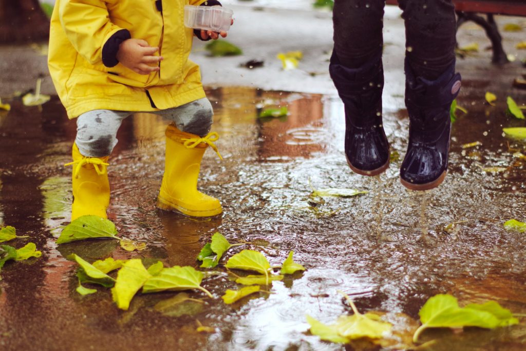 due bambini che saltano nella pioggi: rispettare i tempi dei bambini è parte importante del metodo Montessori