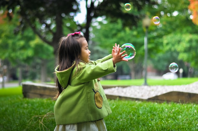 Una bambina che gioca con una bolla di sapone. Questa immagine rappresenta il periodo sensitivo dell'esplorazione sensoriale