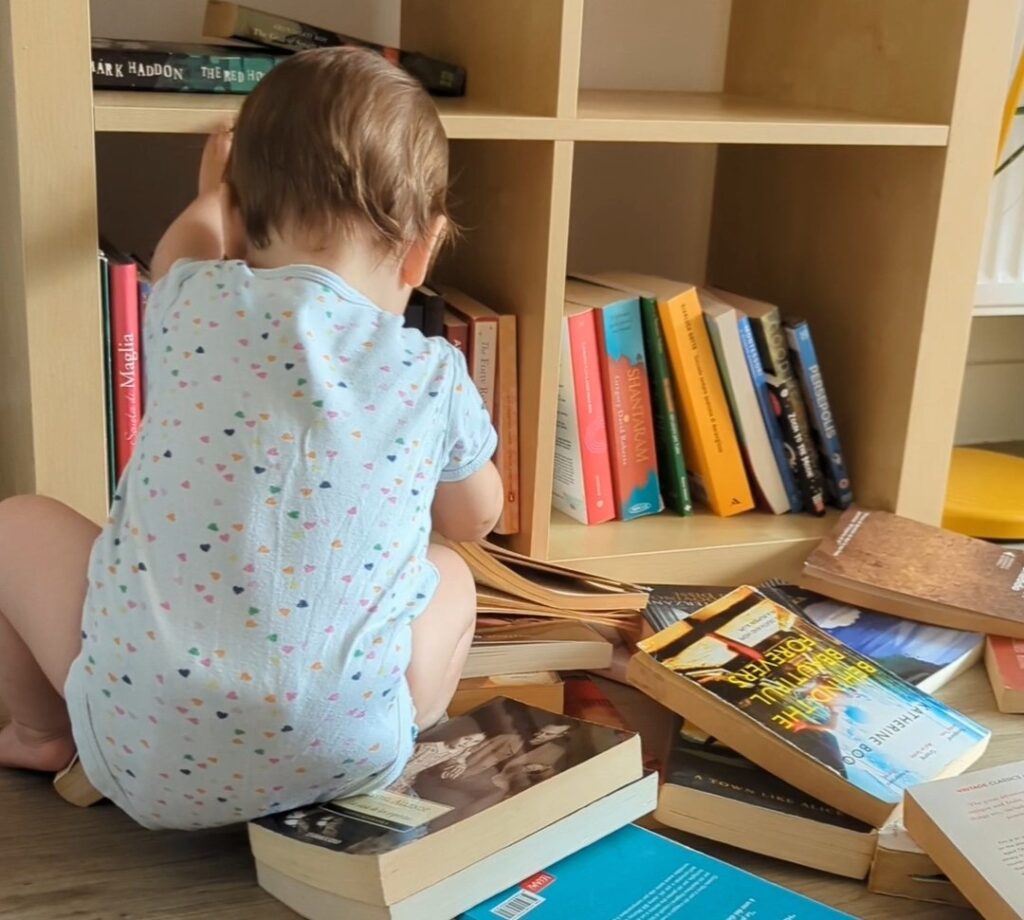 bambina che svuota i libri dallo scaffale di una libreria