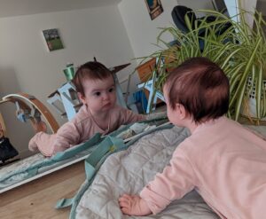 Bambina che si guarda allo specchio durante il tummy time