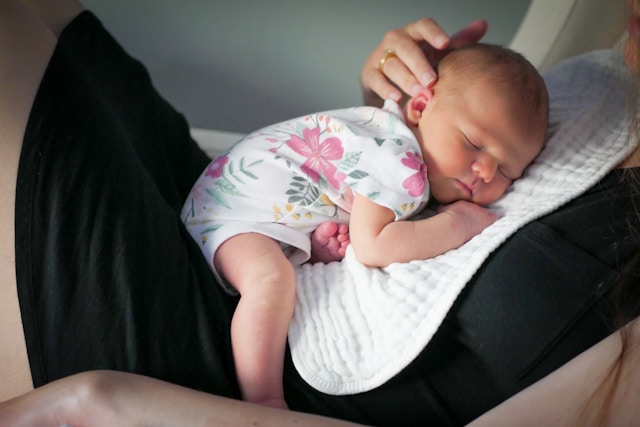 Neonato che dorme serenamente sul petto del genitore, simbolo di contatto, sicurezza e amore durante i risvegli notturni.