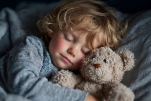 bambino che dorme abbracciando un orsacchiotto