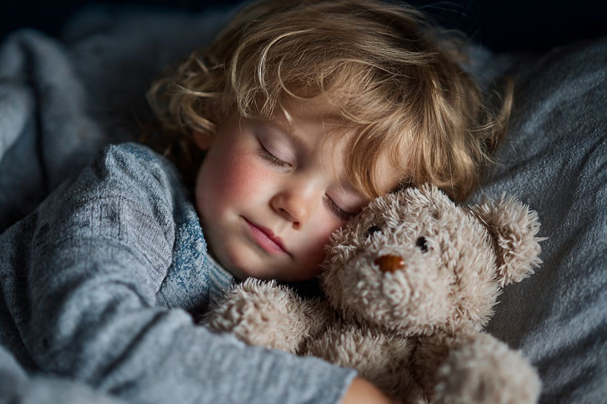 bambino che dorme abbracciando un orsacchiotto