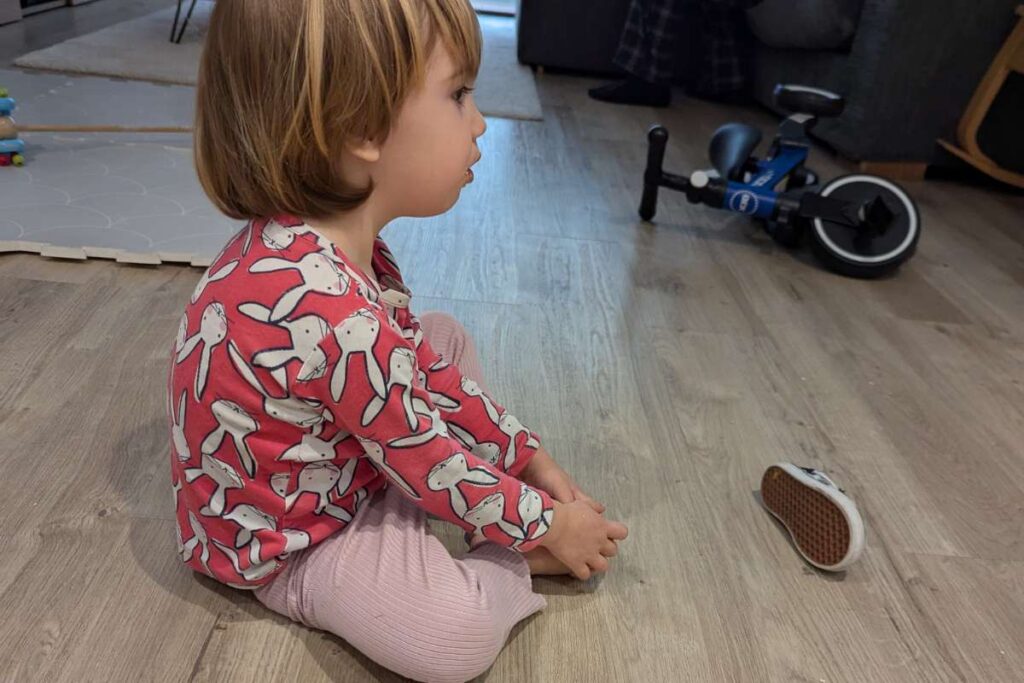 bambina seduta a terra con gambe incrociate