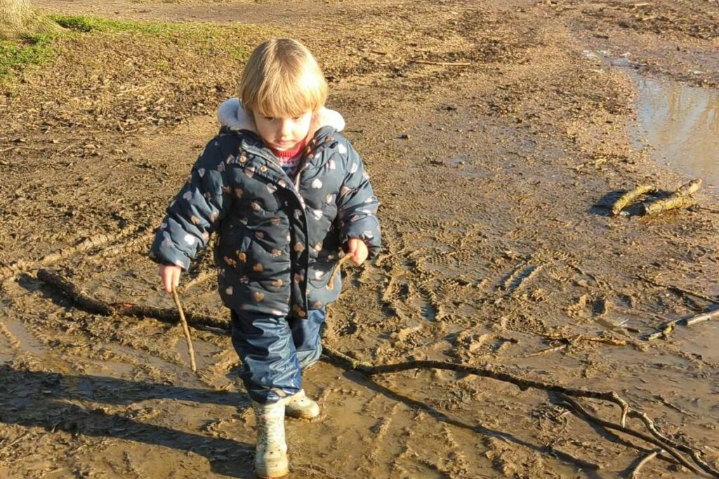 Bambina he cammina al parco su una strada fangosa