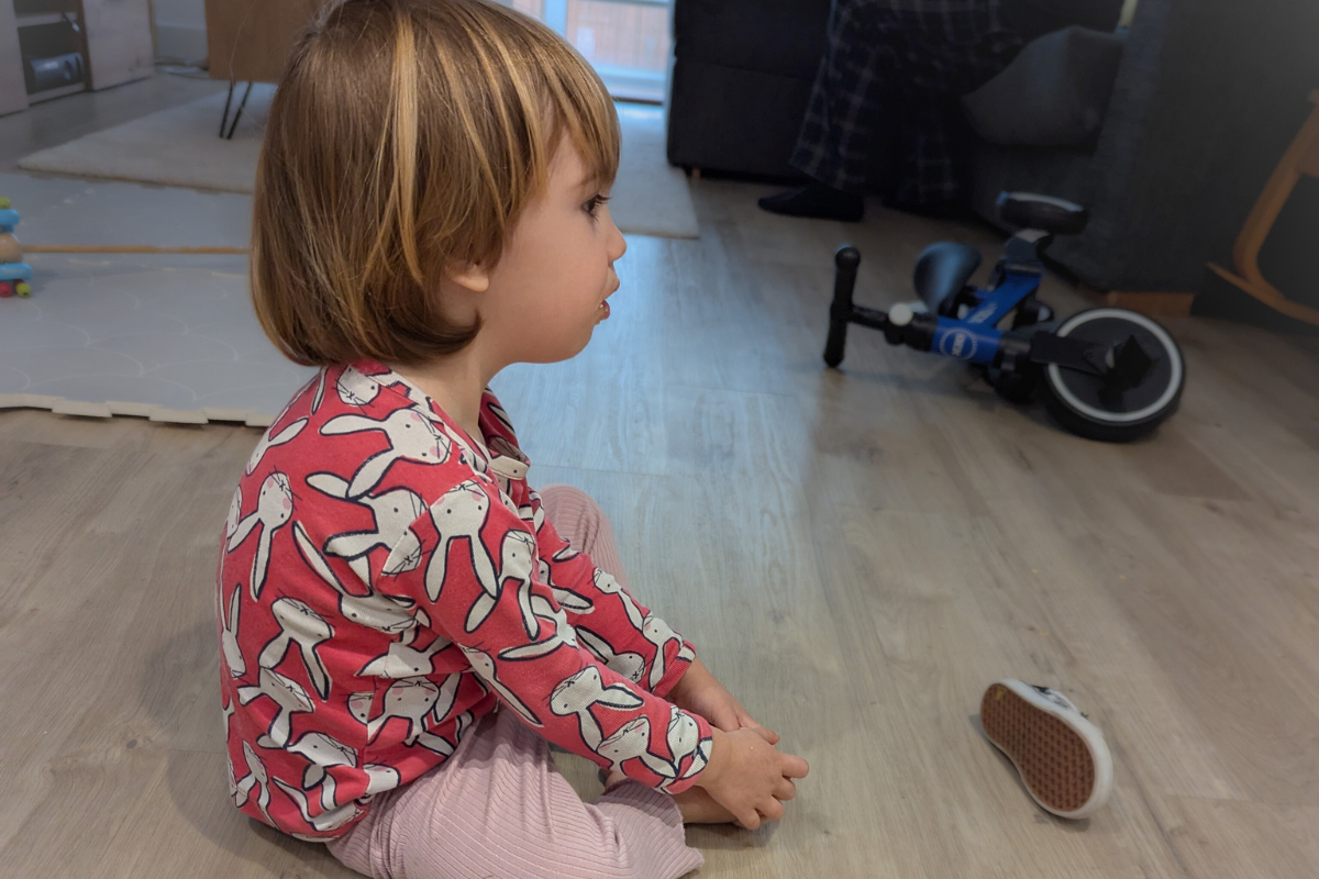 bambina seduta a terra con gambe incrociate