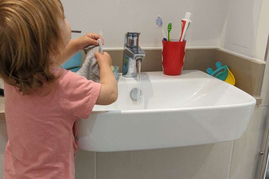 Bambina di spalle che si lava le mani