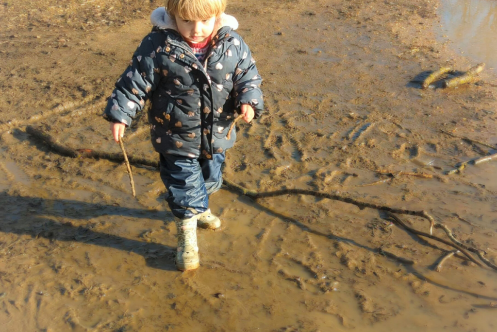 Bambina he cammina al parco su una strada fangosa