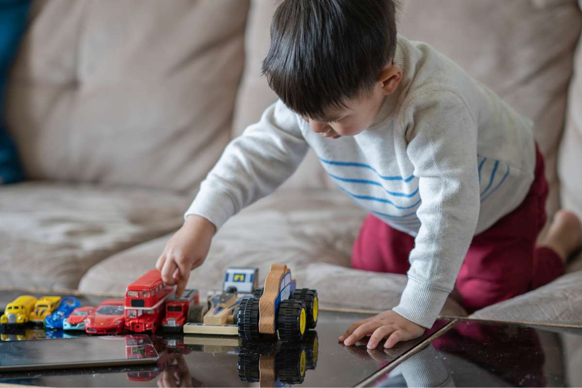 bambino 3-4 anni che gioca da solo con le macchinine