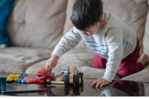 bambino 3-4 anni che gioca da solo con le macchinine