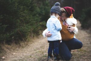 Mamma con due bambini di età diverse abbraccia entrambi