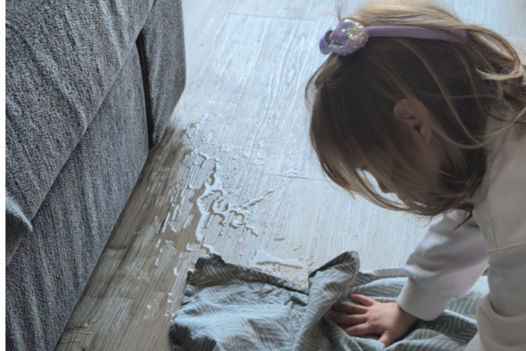 Bambina asciuga il pavimento dopo aver versato dell'acqua