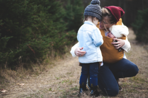 Mamma con due bambini di età diverse abbraccia entrambi