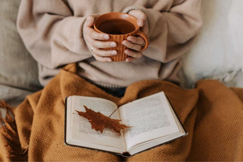 donna con in mano una tazza di caffe e un libro