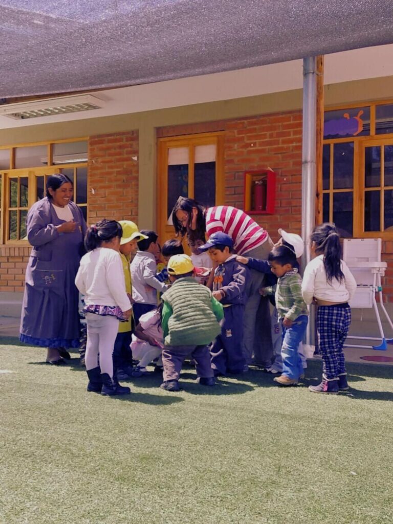 Foto di Raffaella Rossi circondata dai bambini di una scuola materna in Bolivia