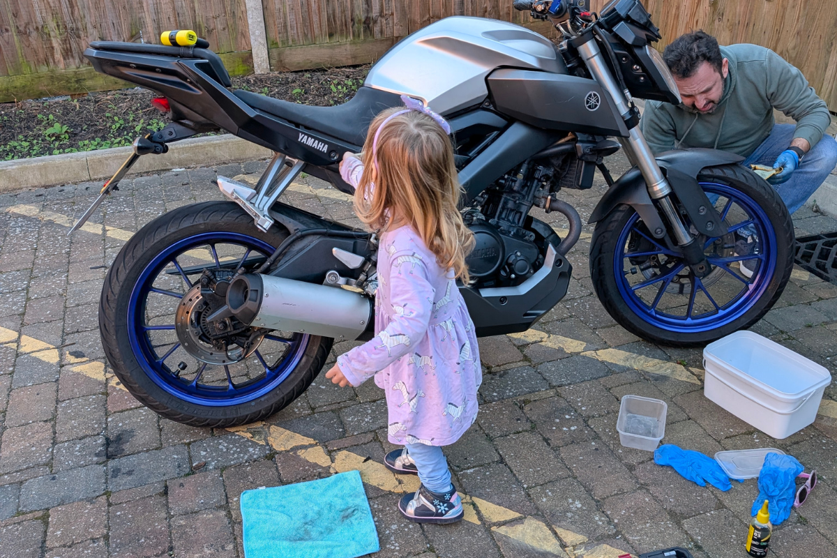 Bambina che aiuta il papa a pulire la moto