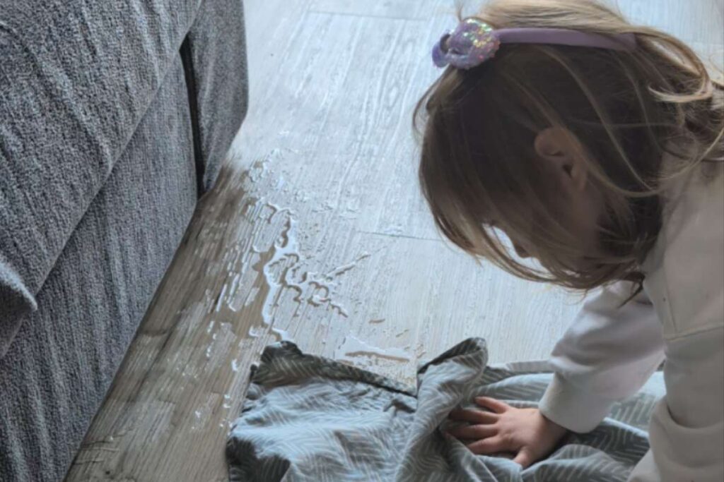 Bambina asciuga il pavimento dopo aver versato dell'acqua