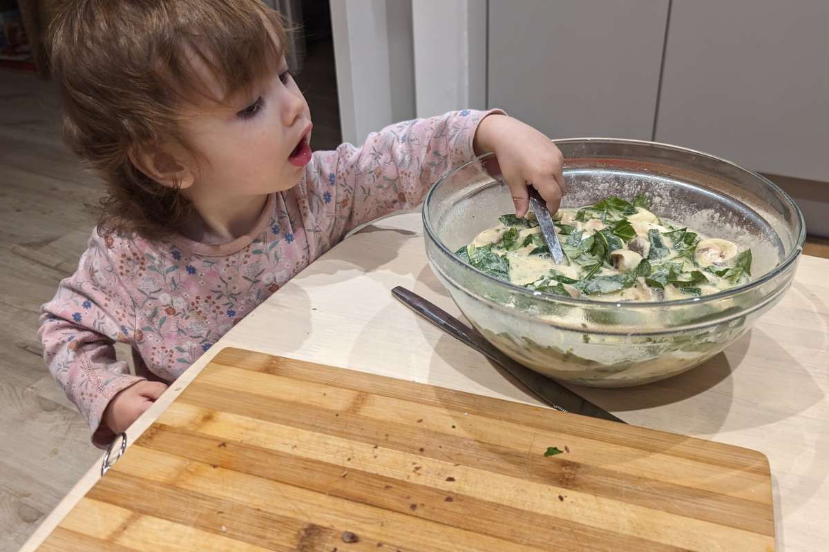 Bambina che con il cucchiaio mescola il contenuto di una ciotola