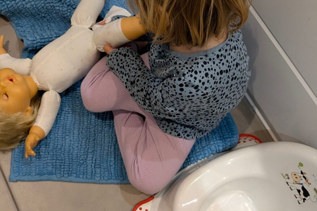 Bambina seduta a terra con un vasino vicino
