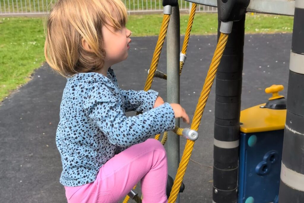 Bambina si arrampica al parco